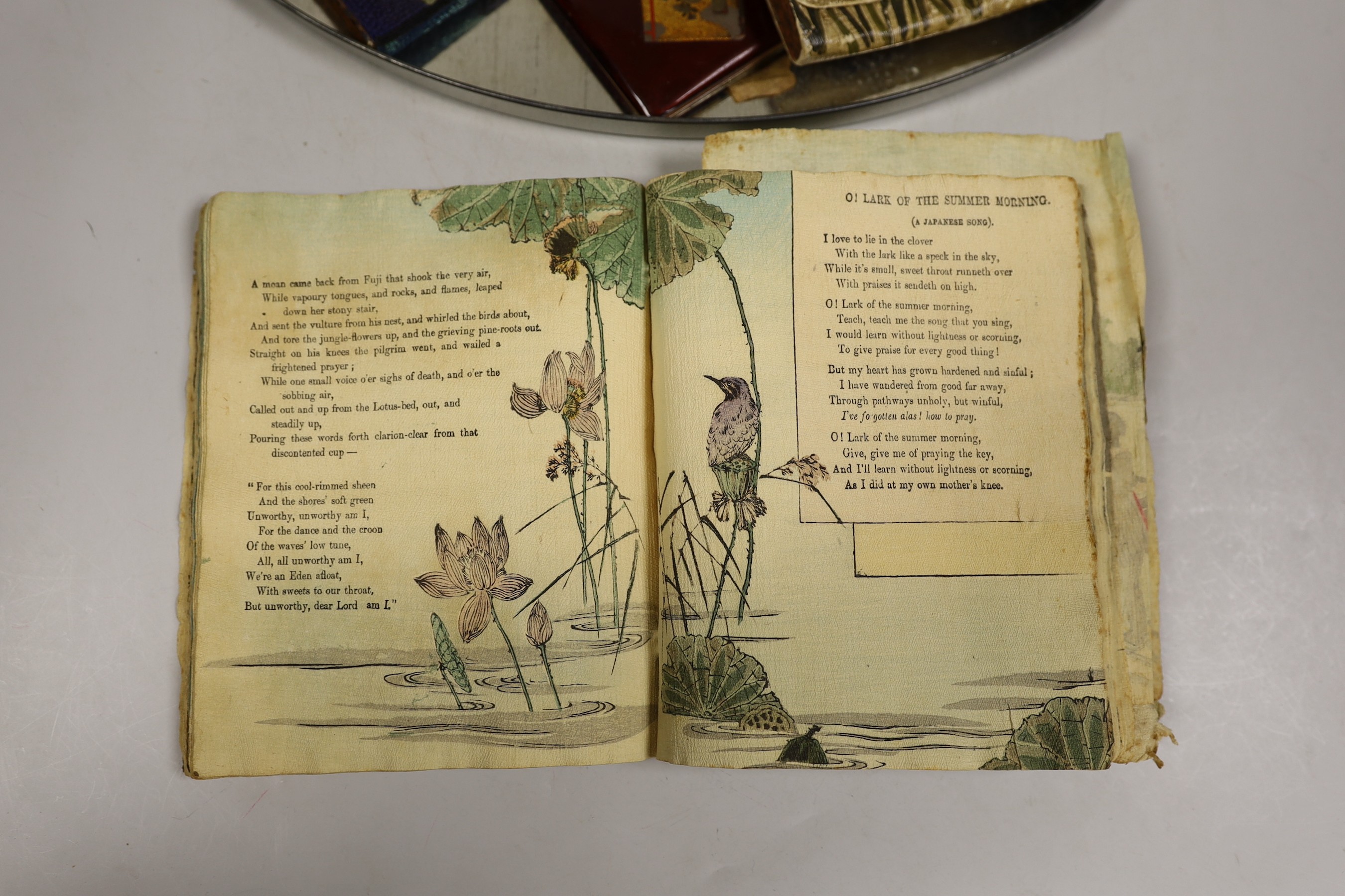Two crepe paper Japanese illustrated books, a Japanese enamel compact two lacquer boxes and covers and two Japanese tobacco pouches, one with ivorine manju netsuke and the other a carved staghorn netsuke of Daikoku